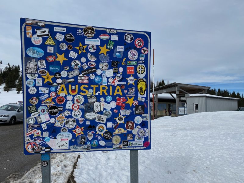 Austrian border crossing board with EU stars on blue background. The board is covered with badges and stickers