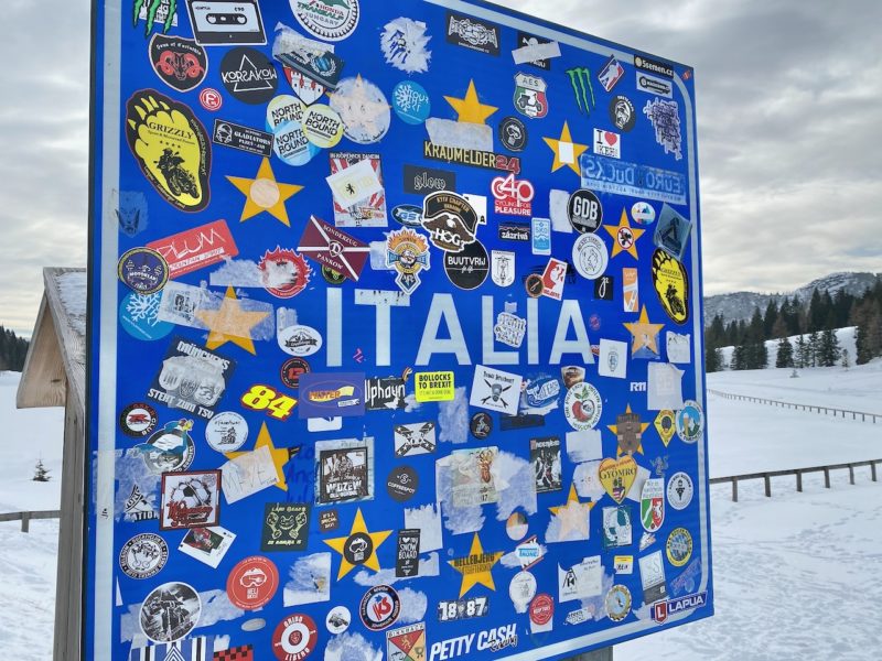 Italian border crossing board with EU stars on blue background. The board is covered with badges and stickers