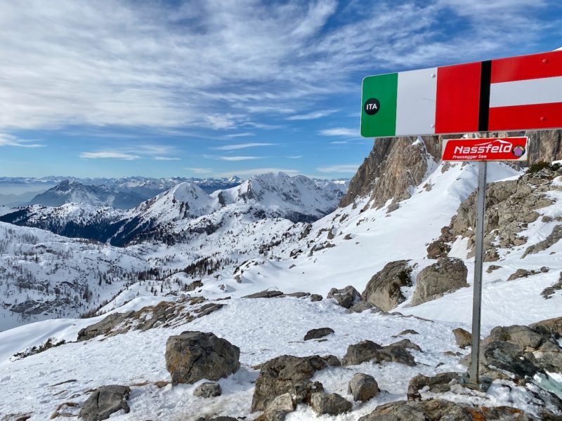 Mountaintop Italian Austrian border showing Italian flag on the left and Austrian flag on the right